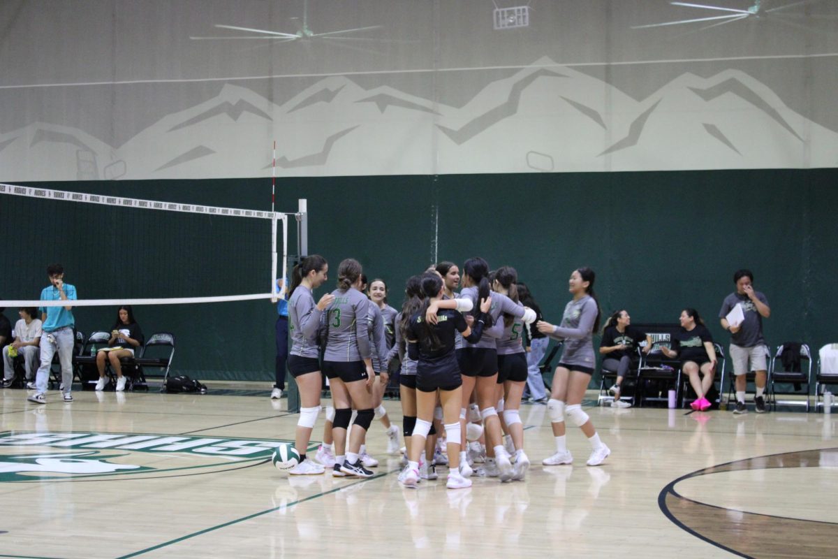 The freshmen volleyball team gathering together after scoring a point.