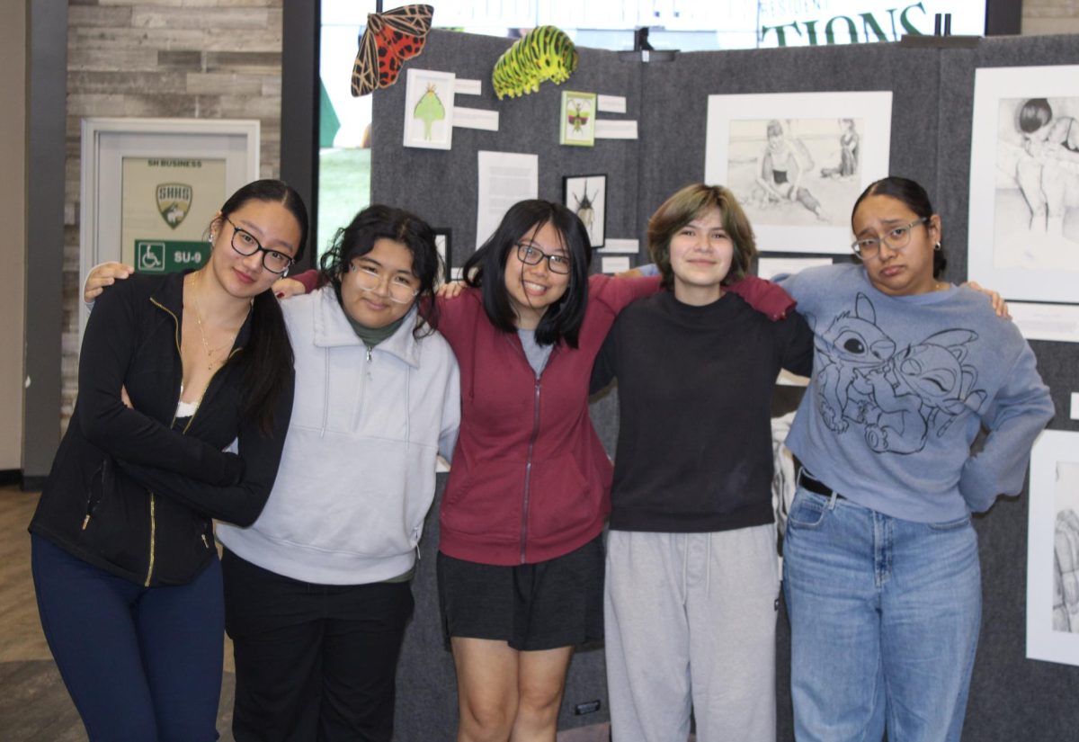 From left to right, Jade Niu (12), Julianne Pasiwen (12), Kristy Pham (12), Evolyth Garcia (10), and Samira Cansino-Chavez (12) pose in front of their exhibition pieces at the student union. 